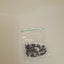 Small black objects in a clear plastic bag on a beige background